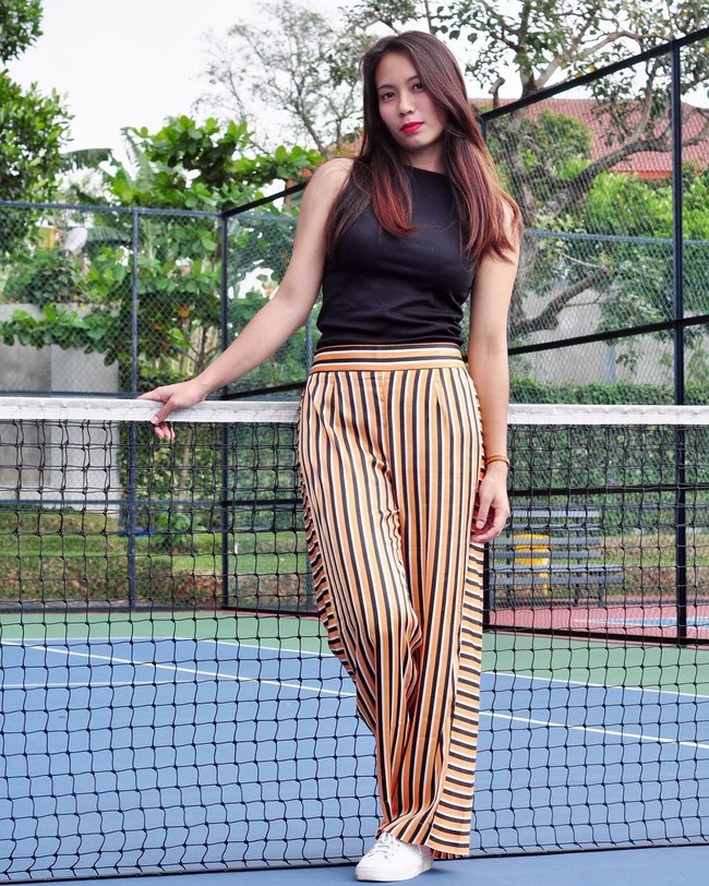 Memiliki lebih dari 172 ribu pengikut di Instagram, Sheila kerap mengunggah fotonya saat off the field atau ketika tidak bertanding voli. Seperti di foto ini, dia bergaya dengan celana lurus garis-garis dengan atasan hitam tanpa lengan. Foto: Dok. Instagram Berllian Marsheilla