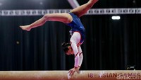 Seorang pesenam pamer keseimbangan di balance beam.