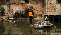 Petugas mengangkut sampah dibataran kali dekat pemukiman padat warga.