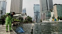Petugas lainnya mencoba mengangkut sampah yang mengapung di kolam.