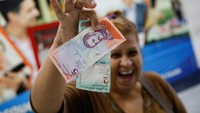 Warga Venezuela memamerkan bolivar baru pecahan 2 dan 5.
