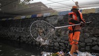Petugas mengangkut sampah di Kali Item dengan alat yang sederhana.