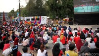 Mereka nonton dengan duduk lesehan di depan layar raksasa.