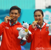 Indonesia juga memperoleh medali emas dari tenis ganda campuran, lewat duet Christopher Rungkat dan Aldila Sutjiadi. Keduanya berhasil menang atas pasangan Thailand Sonchat Ratiwatana/Luksika Kumkhum, dengan tiga set. Ini gaya mereka yang berbarengan mengigit medali. Foto: Rachman Haryanto