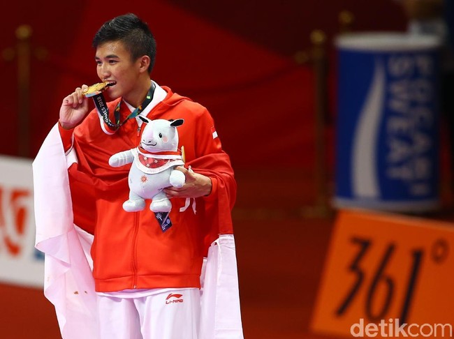 Karateka Rifki Ardiansyah Arrosyid juga menyumbangkan medali emas di kategori kumite 60 kg, setelah menang atas karateka Iran Amir Mahdi Zadeh. Ia berpose dengan menggigit sedikit pinggiran medali emasnya. Foto: Grandyos Zafna