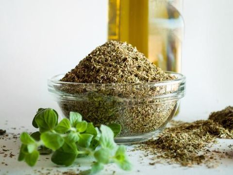 Dry oregano in wooden tea spoon; close up; selective focus;