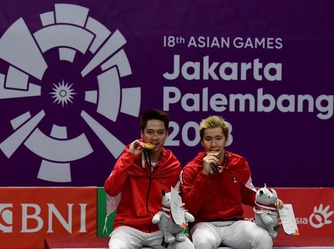 Kalau ini aksi Kevin Sanjaya Sukamuljo dan Marcus Fernaldi Gideon gigit medali, setelah menang dari Fajar Alfian/Muhammad Rian Ardianto di All Indonesian Final ganda putra Asian Games 2018. Rasa bangga tampak terlihat dari wajah Kevin dan Marcus. Foto: Sonny Tumbelaka/AFP Photo