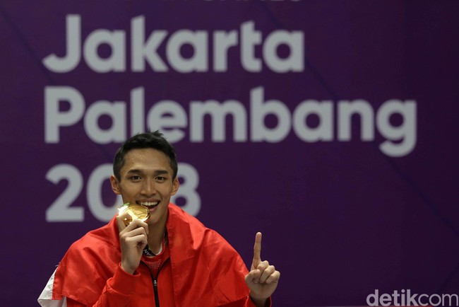 Jonatan Christie yang awalnya tak diunggulkan di cabor bulu tangkis tunggal putra, secara mengejutkan meraih prestasi dengan memperoleh medalis emas untuk Indonesia di Asian Games 2018. Saat medali emas dikalungkan, atlet 20 tahun ini berpose gigit medali sambil mengacungkan telunjuk. Foto: Agung Pambudhy