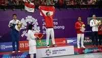 Jonatan Christie naik podium sambil membentangkan bendera merah putih.