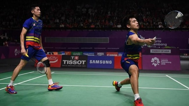 Jersey biru dongker dengan aksen garis kuning dan merah menjadi salah satu pilihan tim badminton Malaysia. Untuk busana pria hadir dalam dua versi, lengan pendek dan lengan buntung. Tidak ketinggalan logo berupa bendera Malaysia di bagian dada kanan. (Foto: AFP)