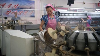 Seorang pegawai yang bekerja di pabrik pengolahan sutera. Foto: Carl Court / Getty Images