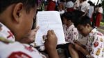 Patut Dicontoh! Siswa SD Ini Menunggu Bus Sambil Belajar