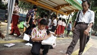 Mereka belajar di antara warga yang lalu lalang di depan halte.