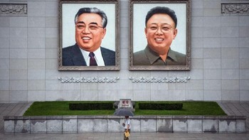 Orang berjalan di bawah gambar besar Kim Ilsung dan Kim Jongil. Foto: Carl Court / Getty Images