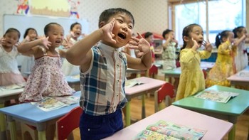 Anak-anak di sekolah yang tengah mengikuti arahan ibu guru. Foto: Carl Court / Getty Images
