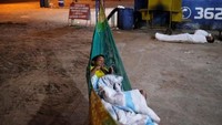 Anak laki-laki Venezuela tidur di tempat tidur gantung pada malam hari di bengkel mobil. Nacho Doce/Reuters.