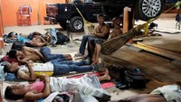 Orang-orang Venezuela tidur pada malam hari di bengkel mobil. Nacho Doce/Reuters.
