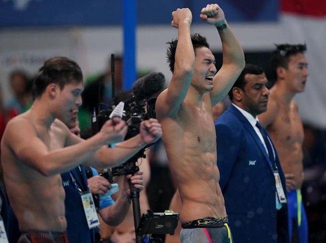 Atlet renang China He Xinyu merayakan kemenangannya setelah memenangkan final 4x100 meter di hari keenam Asian Games 2018. Perut sixpack-nya bisa bikin para pria iri nih. (Foto: Getty Images)