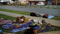 Laki-laki Venezuela tidur di rumput di depan Stasiun Bus antarnegara bagian di Boa Vista, negara bagian Roraima, Brasil. Nacho Doce/Reuters.