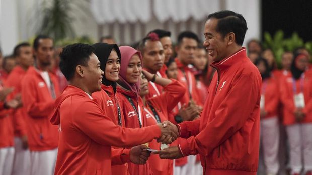 Presiden Joko Widodo (kanan) menyalami dan memberikan buku tabungan kepada lifter Eko Yuli Irawan (kiri) saat pemberian bonus kepada atlet peraih medali di Istana Negara, Jakarta, Minggu (2/9).