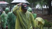 Para penonton ini mengenakan jas hujan.