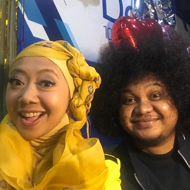 Saat siaran, ia kembali memakai gaya hijab turban kepang. Kali ini ia memakai warna kuning yang cerah mulai dari turban, inner ninja, dan pakaiannya. Foto: Instagram/asri_wales