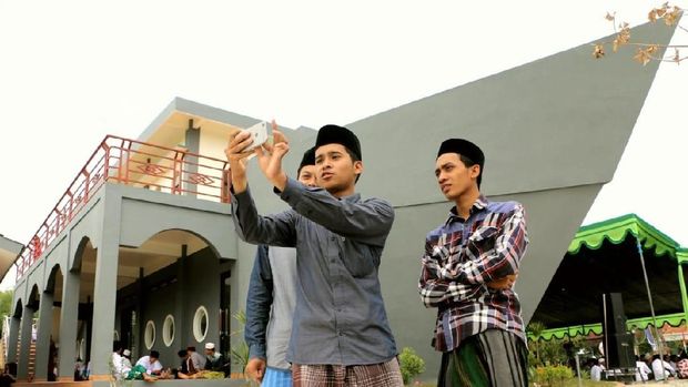 Santri sedang selfie berlatar belakang masjid perahu