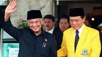 Presiden Indonesia BJ Habibie (kiri) melambai kepada wartawan saat ketua partai  dari partai Golkar Harmoko (kanan) mengantarnya ke mobilnya pada 9 Juli 1998 di Jakarta setelah mereka menghadiri pembukaan kongres luar biasa Partai Golkar  Sidang tersebut dihadiri lebih dari 1000 anggota partai dan bertempat di Hotel Indonesia. AFP/Kemal Jufri