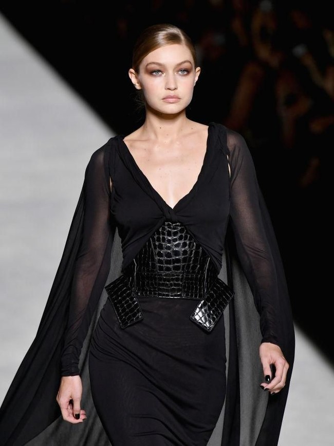Tak cuma di front row, wajah-wajah tenar juga mewarnai catwalk Tom Ford. Salah satunya Gigi Hadid yang mendapat mandat memeragakan gaun hitam bersayap dengan korset kulit buaya. (Foto: Getty Images)