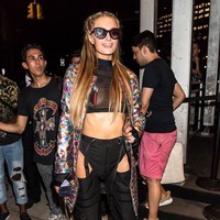 Gaya yang nyeleneh dan berani dari seorang Paris Hilton. Tampil dengan crop top menerawang dan celana cutout. Coat warna-warni ala Jeremy Scott pun menyempurnakan look yang seksi ini. Foto: Getty Images