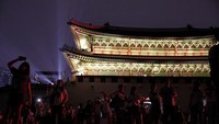 Masyarakat dan pengunjung pun berkumpul untuk menyaksikan hiasan lampu warna-warni yang menghiasi Istana Gyeongbokgung. Woohae Cho/Getty Images.