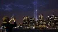 Seorang warga memotret instalasi Tribute in Light di kota New York, Amerika Serikat. Brendan Mcdermid/Reuters.
