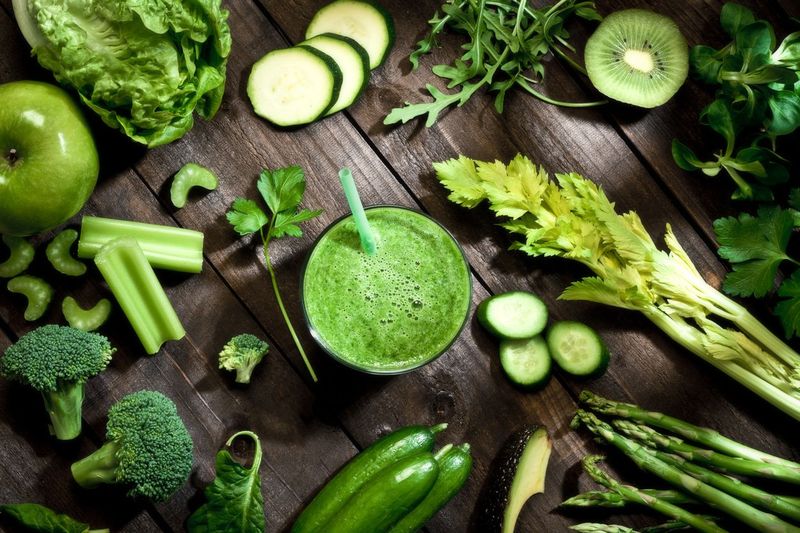 Healthy green vegetables and green fruit smoothie on rustic wood table.