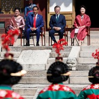 Irianan memadukan kebaya tersebut dengan selendang songket keemasan. Sementara itu, gaya Jokowi konsisten dengan dasi merahnya. (Foto: Jeon Heon-Kyun-Pool/Getty Images)