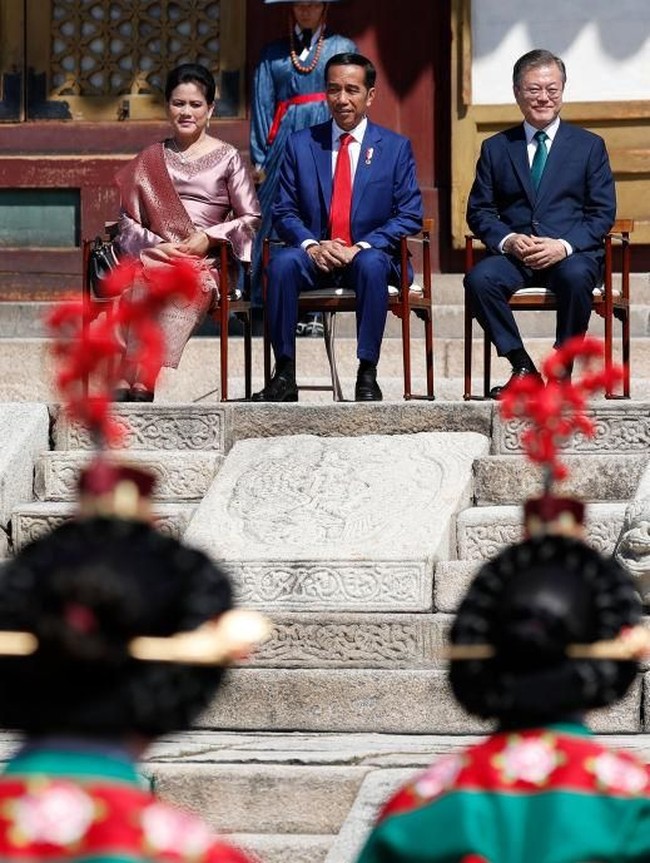 Irianan memadukan kebaya tersebut dengan selendang songket keemasan. Sementara itu, gaya Jokowi konsisten dengan dasi merahnya. (Foto: Jeon Heon-Kyun-Pool/Getty Images)