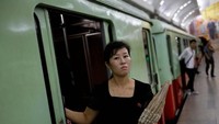 Sambil memegang payung, seorang penumpang perempuan nampak turun dari kereta bawah tanah di Pyongyang. Reuters/Danish Siddiqui.