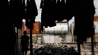 Siluet warga yang sedang beraktivitas dengan kondisi dipinggir rel dan lokasi penyimpanan peti kemas.