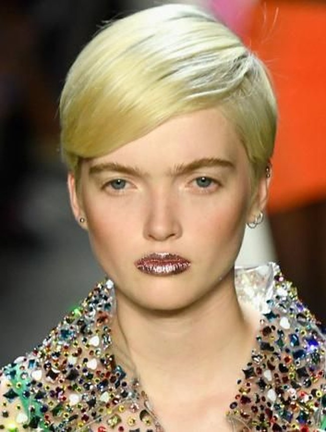 Bibir bertekstur bling-bling hadir di New York Fashion Week 2019 untuk memberikan opsi lain dari pulasan lipstik. Dalam fashion show Jeremy Scott, para modelnya tampil dengan bibir glitter. Tanpa makeup mata sekalipun, hanya dengan tampilan lipstik plus taburan glitter mampu memberikan tampilan yang stand out.  Foto: Getty Images