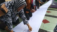 Seorang pendemo membubuhkan jam jempol darah ke kain putih.