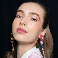 Makeup glass skin saat ini tengah jadi tren kecantikan. Desainer Badgley Mischka tak hanya memberikan tampilan sebening kaca pada kulit wajah model, namun sentuhan gelas mengkilap juga ditampilkan di seluruh wajahnya. Eyeshadow dan lipstik glossy menyempurnakan penampilan glass skin.  Foto: Getty Images