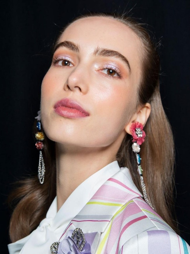 Makeup glass skin saat ini tengah jadi tren kecantikan. Desainer Badgley Mischka tak hanya memberikan tampilan sebening kaca pada kulit wajah model, namun sentuhan gelas mengkilap juga ditampilkan di seluruh wajahnya. Eyeshadow dan lipstik glossy menyempurnakan penampilan glass skin.  Foto: Getty Images