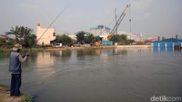 Seorang warga memancing di Sungai Kalimalang.