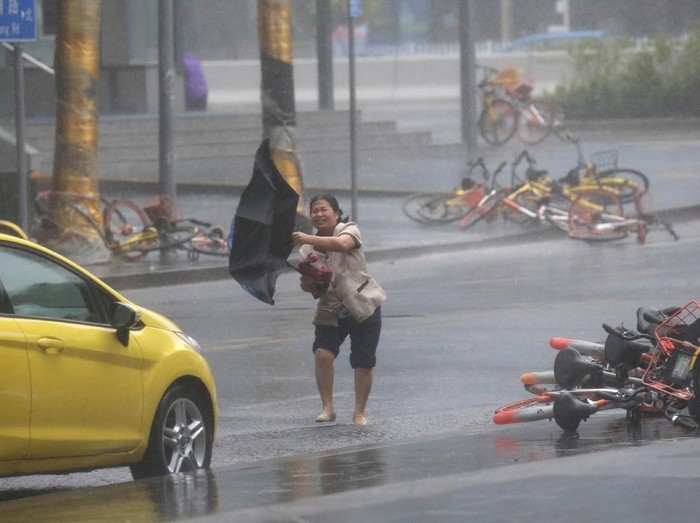 A woman almost falls down near a broken tree in the rainstorm as Typhoon Mangkhut approaches, in Shenzhen, China September 16, 2018. REUTERS/Jason Lee