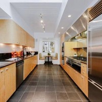 Dapur nan luas yang didominasi elemen kayu serta keramik hitam pada lantainya. Dapur dilengkapi kabinet panjang, oven besar, kulkas jumbo dan tempat makan ala diner, jika sang pemilik rumah ingin langsung sarapan atau ngemil setelah masak. Foto: Dok. Trulia, Dok. Sothebys International Realty