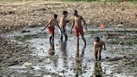 Sejumlah anak-anak tampak asyik bermain di sebuah empang ikan yang kering di wilayah Koja, Jakarta Utara, Senin (17/9/2018).