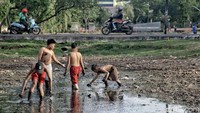 Agar tak mengotori pakaian mereka, anak-anak ini pun memilih tak mengenakan baju saat bermain di empang yang kering tersebut.