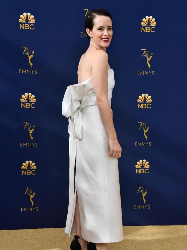 Pemeran Ratu Elizabeth II di serial The Crown, Claire Foy, tampil flawless dengan gaun muncul dengan gaun minimalis Calvin Klein yang dihiasi aksen pita bergaya struktural di belakangnya. (Foto: Getty Images)