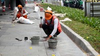 Pekerja saat memperbaiki sejumlah trotoar yang rusak.