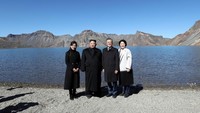 Kedua pemimpin bersama Ibu Negara Korea berfoto bersama dengan latar belakang pemandangan pegunungan Gunung Paektu yang indah. Pyeongyang Press Corps/Pool via Reuters.