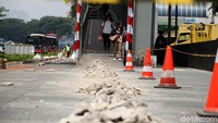 Pejalan kaki melintas diantara trotoar yang sedang diperbaiki.